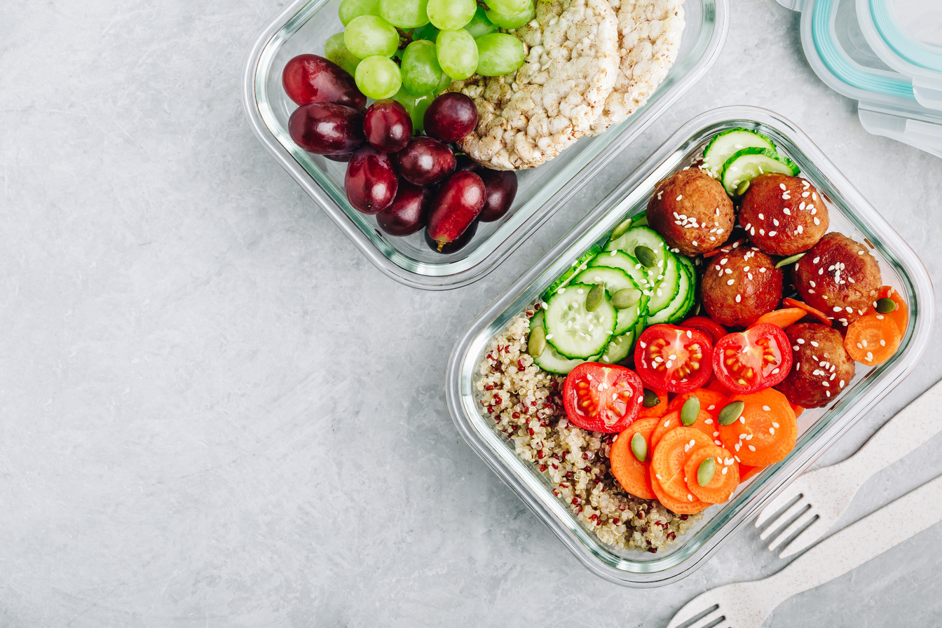 Meal prep lunch box containers with quinoa, meatballs cucumbers, carrots and pumpkin seeds